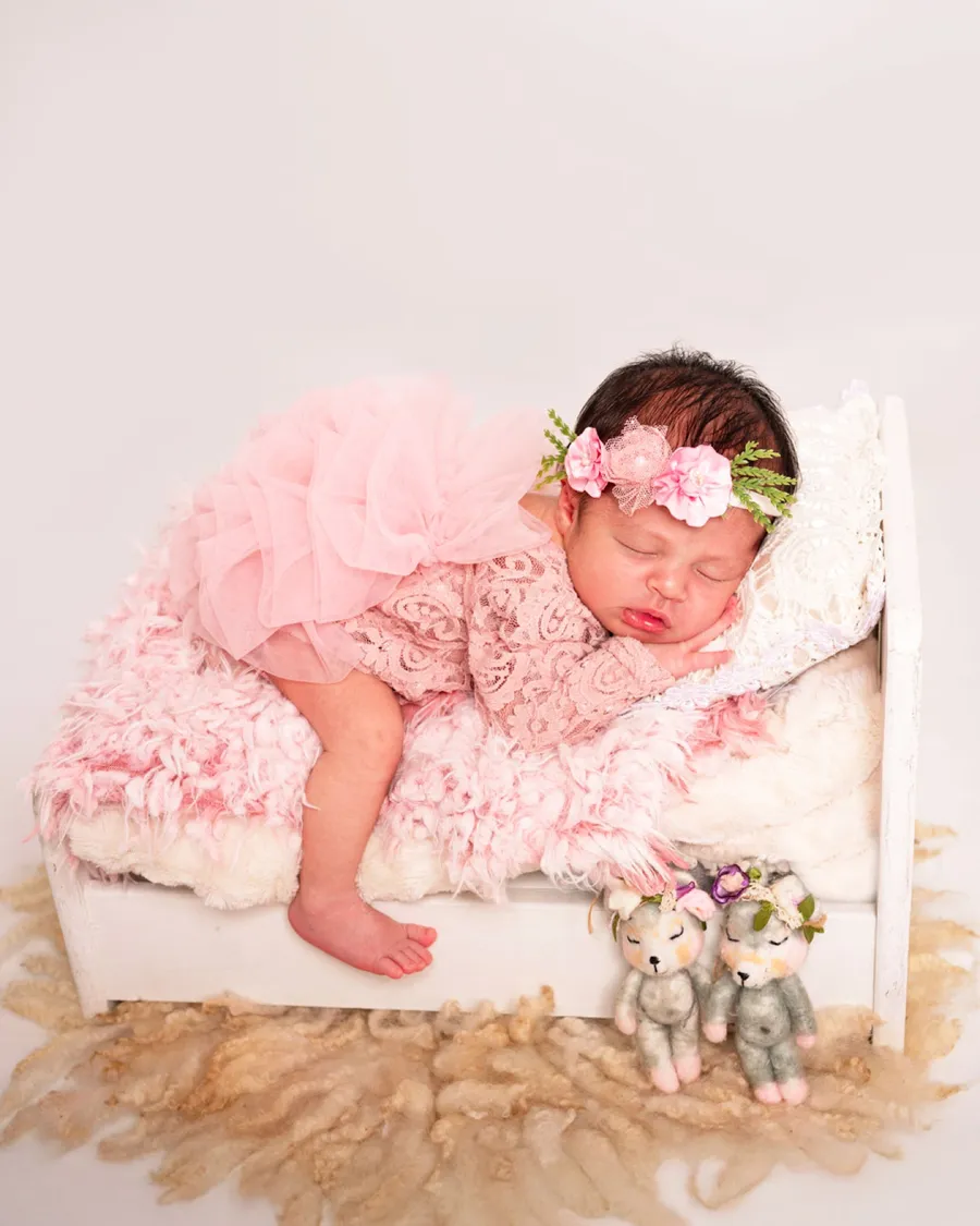 Recién nacida con tutú rosado durmiendo en una camita blanca